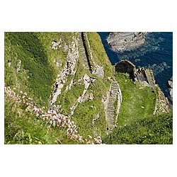  - Man walking down steep stone steps to cove harbour carved out of seacliff  photo 